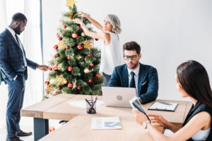 young multicultural businesspeople working and christmas tree in office